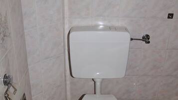Un bagno con un water, un cestino e una spazzola per il water.