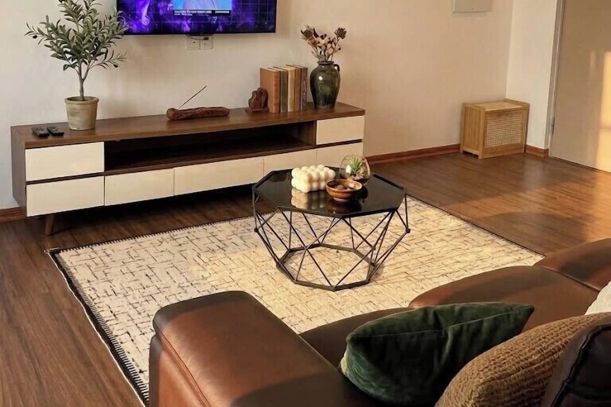 A modern living room with a flat-screen TV, a sofa, a coffee table, and a bookshelf.