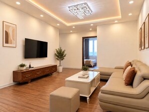 A modern living room with a flat-screen TV, a sofa, a coffee table, and a cabinet.