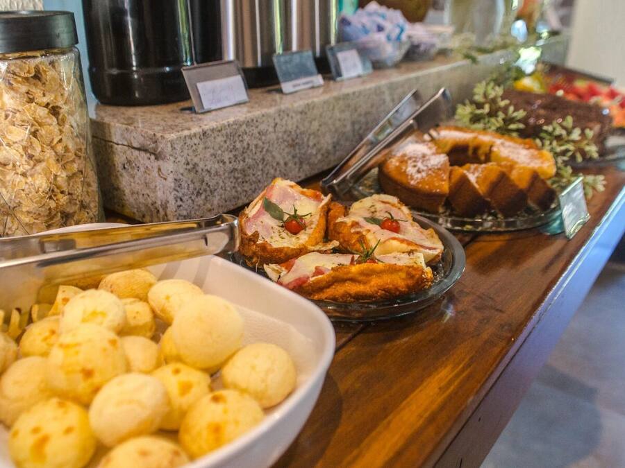 Un bufé con diversos alimentos, como pan, un bol de bolitas de queso y un recipiente con cereal.