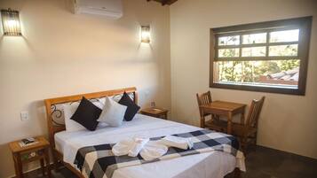 A hotel room with a bed, a table, and a window.