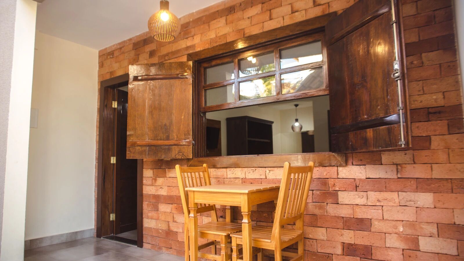 A kitchen with a brick wall, wooden cabinets, a window, and a dining table with chairs.