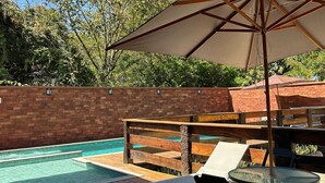 Un espace piscine agrémenté d’un mur en briques, d’une terrasse en bois et de mobilier d’extérieur.