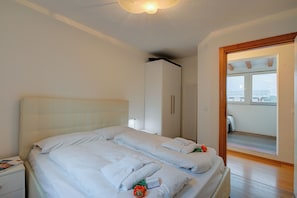 A hotel room with two beds, a wardrobe, a nightstand, and a view of the outside. - Torbole Lake Front (Arco)
