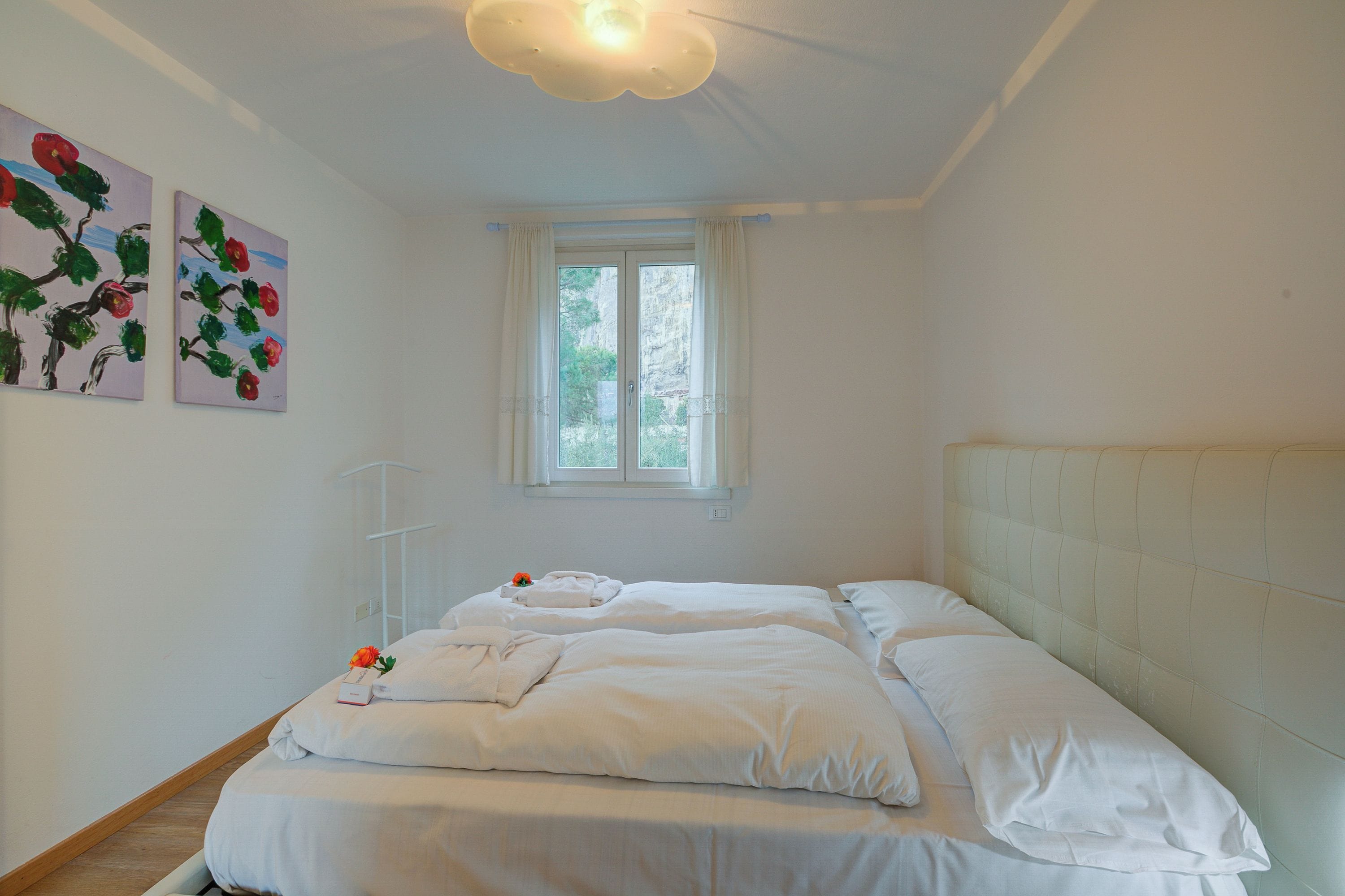 Une chambre avec deux lits, une fenêtre et des œuvres d’art murales.