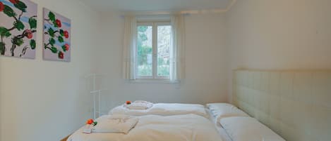 A bedroom with two beds, a window, and wall art.