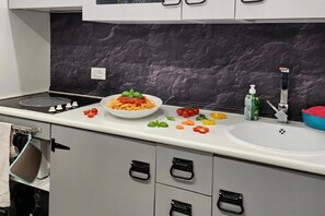 A kitchen with a stove, sink, and cabinets. - Apt Suite 125 Shared Pool & sun Terrace (Gardone Riviera)