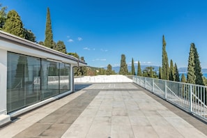 A rooftop terrace with a clear view of the surrounding landscape, including tall trees and distant mountains. - Apt Suite 125 Shared Pool & sun Terrace (Gardone Riviera)