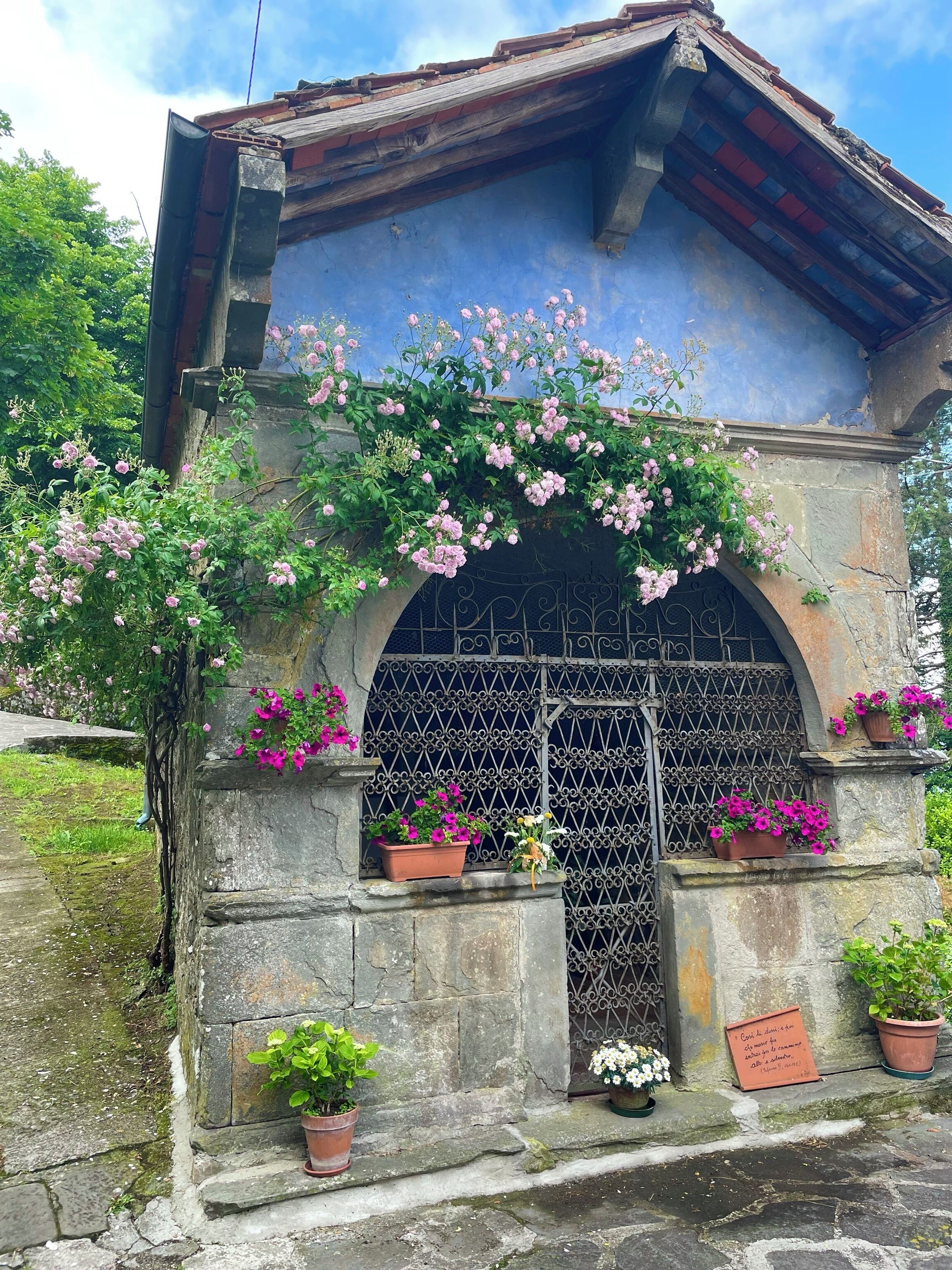 A stone structure with a metal gate, potted plants, and a plaque.