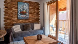 Ein modernes Wohnzimmer mit einer Holzverkleidung, einer Couch, einem Couchtisch und einer Glastür, die zu einem Außenbereich führt.