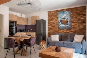 Une cuisine moderne avec des meubles en bois, un coin repas avec une table et des chaises en bois, un canapé gris et une table basse en bois.