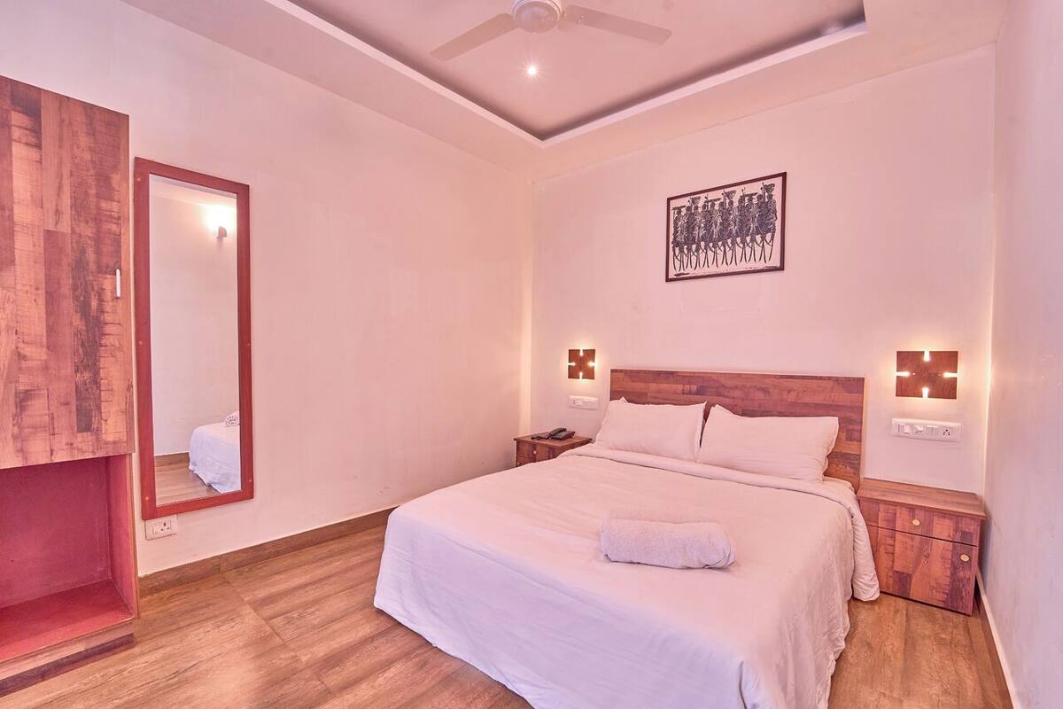 Un dormitorio con una cama grande, cabecera de madera, mesitas de noche, un espejo y un ventilador de techo.
