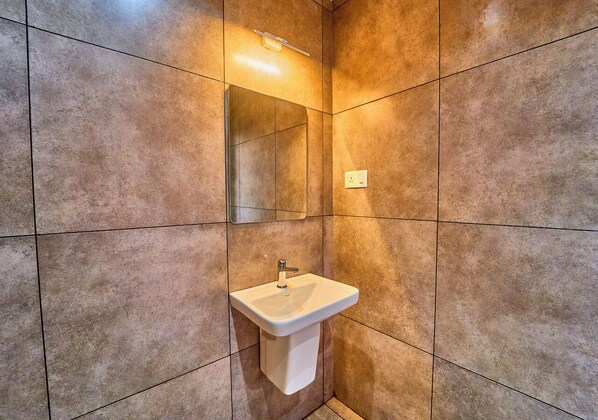 Une salle de bain avec un lavabo, un miroir et des murs carrelés.