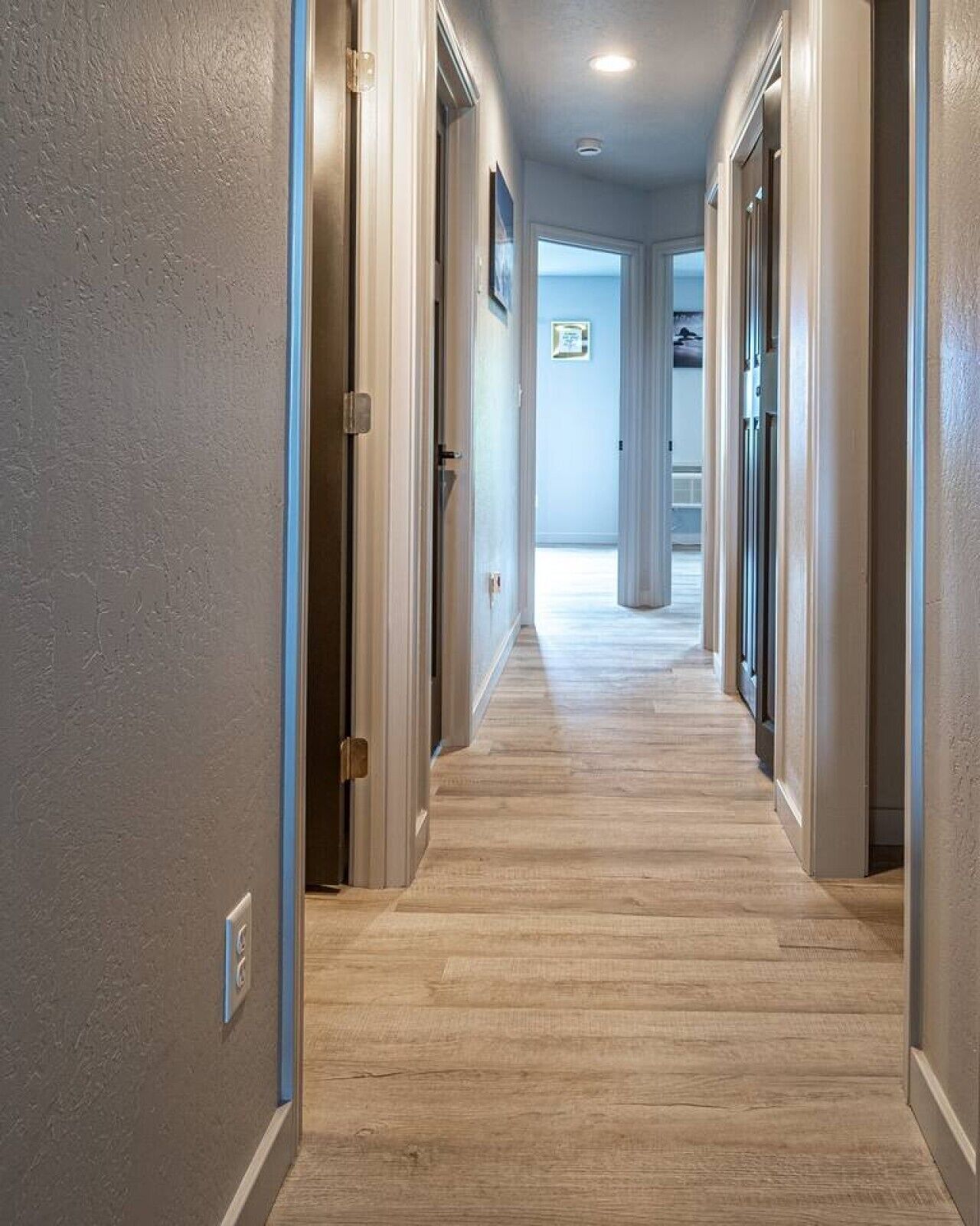 Um corredor com piso de madeira e portas em ambos os lados.