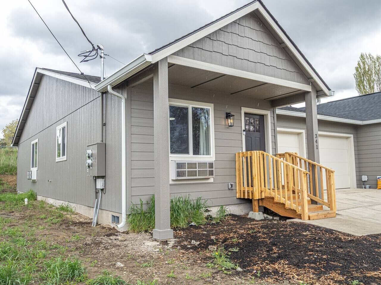 A residential house with a covered porch, a garage, and a visible electrical box.