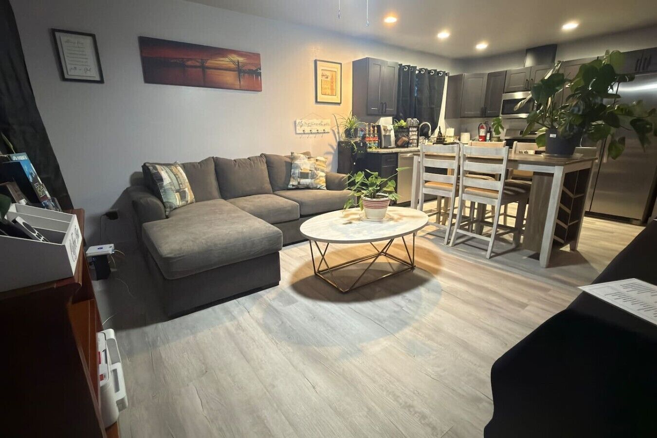 A modern living room with a grey sofa, a round coffee table, and a dining area with a white table and chairs.
