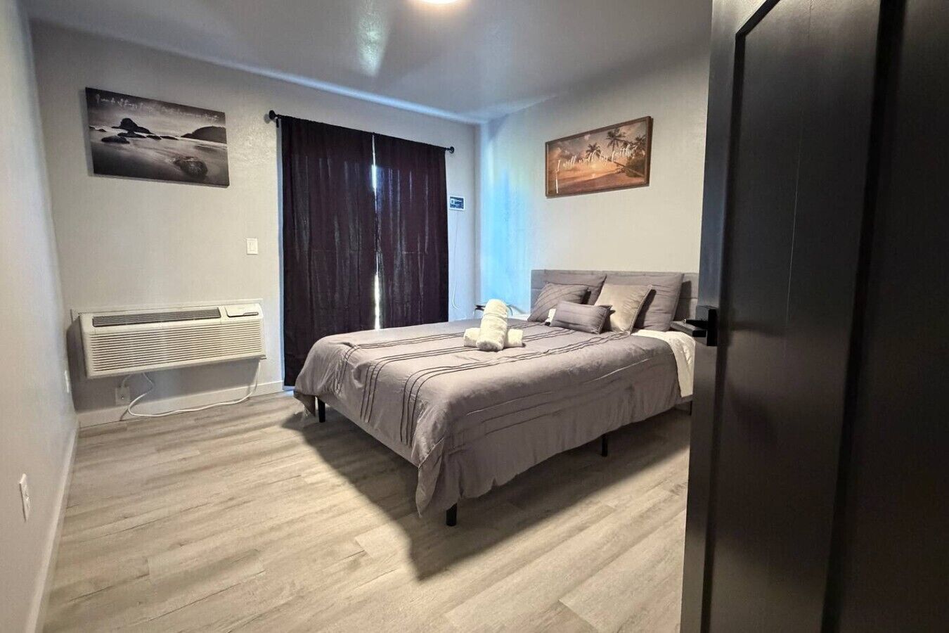 Quarto com cama, radiador, janela com cortinas e duas pinturas penduradas na parede.