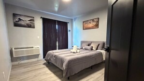 Une chambre à coucher comprenant un lit, un radiateur, une fenêtre avec des rideaux et deux tableaux accrochés au mur.
