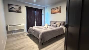 Quarto com cama, radiador, janela com cortinas e duas pinturas penduradas na parede.