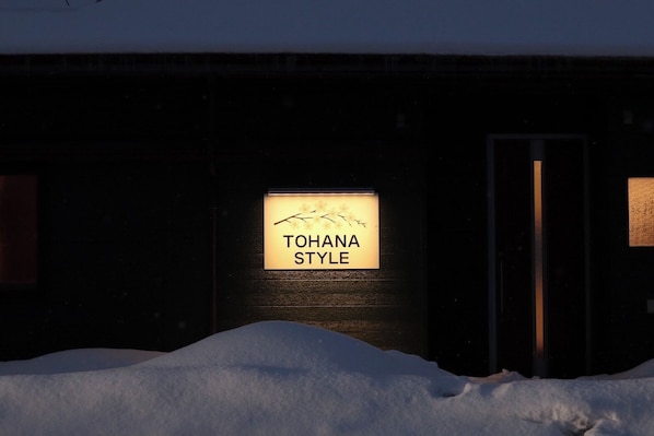 A building with a sign reading 'TOHANA STYLE' illuminated in the dark.