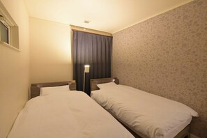 A hotel room with two single beds, a nightstand, a lamp, a window with curtains, and a floral-patterned wall. - Maximum 12 guests | 131 sq m private house | Free  / Nagoya City Aichi (Nagoya City)