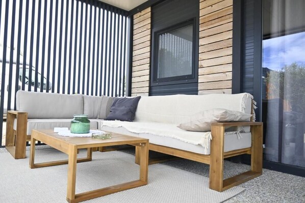 A modern outdoor seating area with a wooden bench, a cushioned sofa, and a coffee table. - View Sunce i More Premium Mobilehome (Pirovac)
