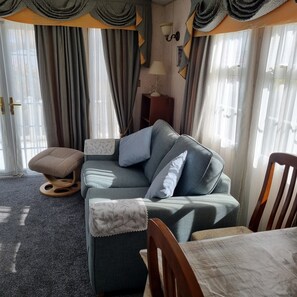 A cozy living room with a sofa, a wooden chair, a small table, and a lamp.