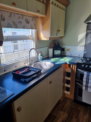 A kitchen with a sink, a stove, and a window overlooking a balcony.