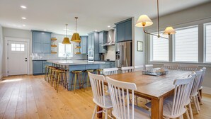 A modern kitchen with blue cabinets, a wooden dining table, white chairs, and pendant lighting. - 'Bearly Behaven' Near Bear Lake & Marina! (Garden City)