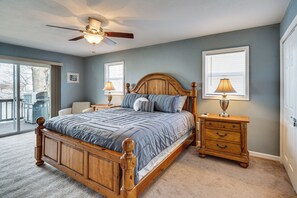 Een slaapkamer met een houten bed, twee nachtkastjes, een plafondventilator en uitzicht.