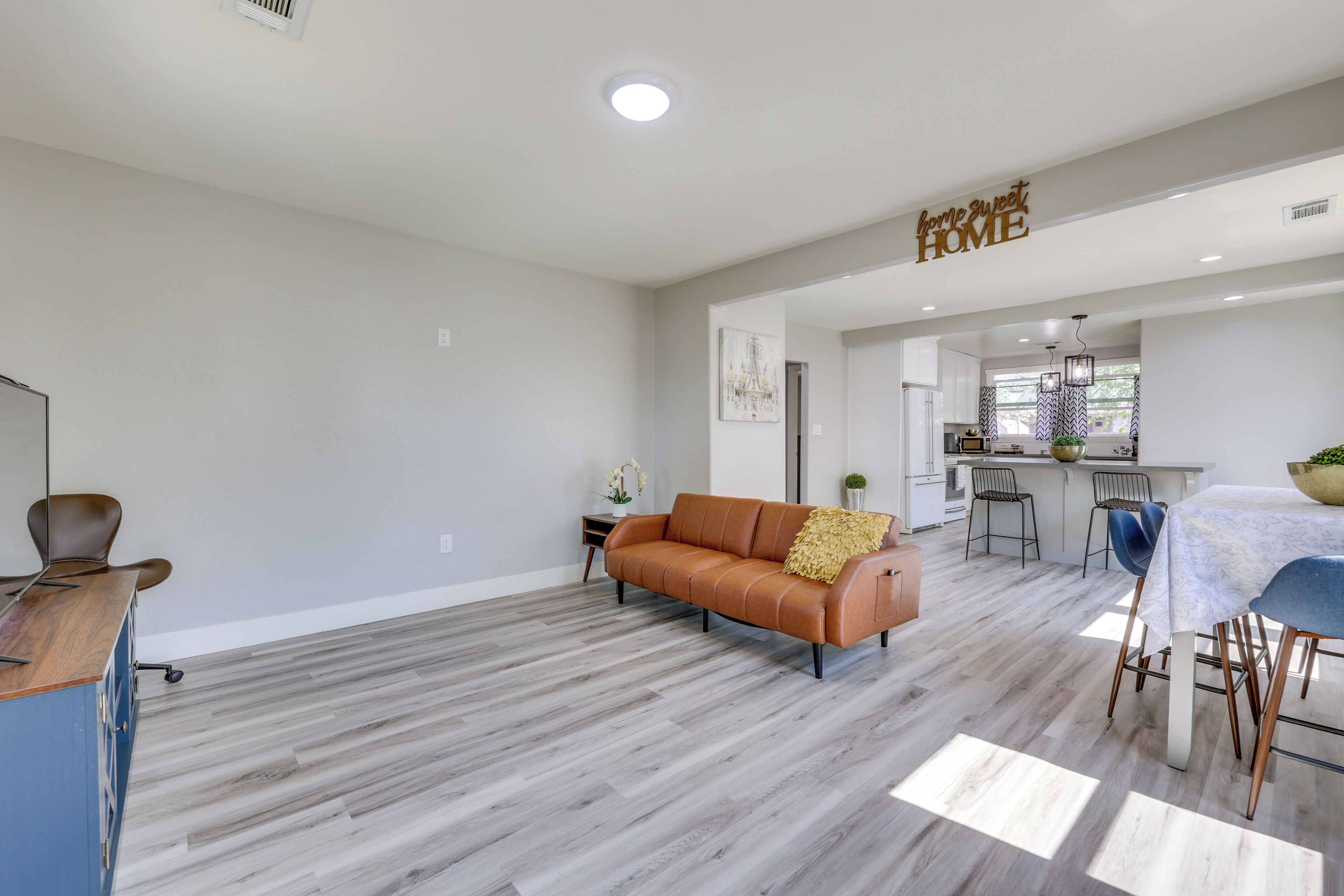 A spacious living area with a sofa, dining table, and kitchen in the background.