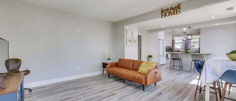 A spacious living area with a sofa, dining table, and kitchen in the background.