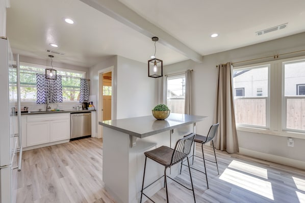 A modern kitchen with a central island, bar stools, and pendant lighting.