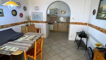 A compact living space with a dining area, kitchen, and a small table with a chair.