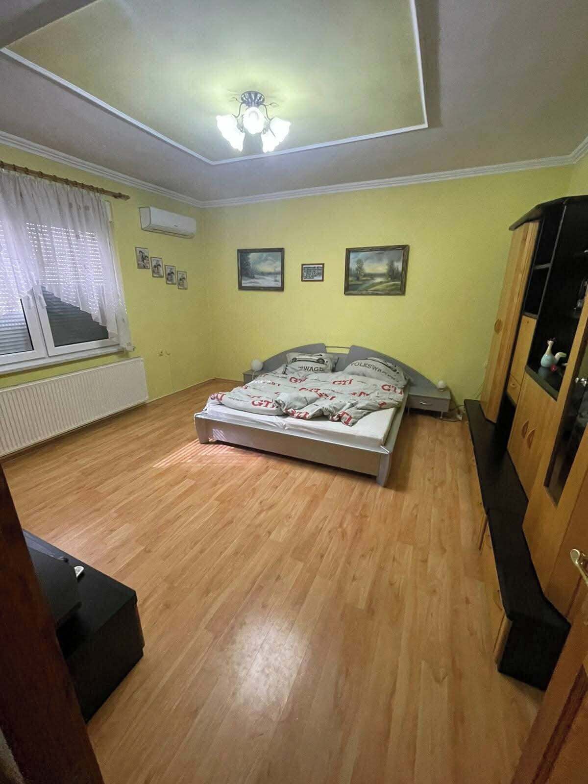 Un dormitorio con cama, radiador, ventana con cortinas y ventilador de techo.