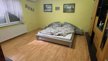 Un dormitorio con cama, radiador, ventana con cortinas y ventilador de techo.