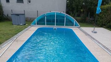 Une piscine rectangulaire dotée d’une enceinte en verre, entourée d’une terrasse en galets.