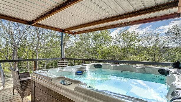 Een hottub op een houten terras met uitzicht op bomen.