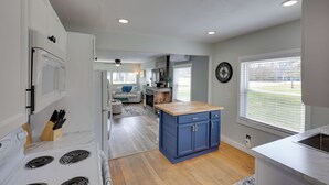 A modern kitchen with a central island, white cabinets, and a dining area with a sofa and table. - Near Pine Knob, Lakes & Trails! Ortonville Getaway (Ortonville)