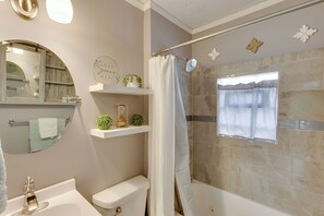 A bathroom with a toilet, sink, shower, and a window with a curtain. - Near Pine Knob, Lakes & Trails! Ortonville Getaway (Ortonville)