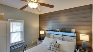 A bedroom with a bed, two bedside tables with lamps, a ceiling fan, a window with blinds, and a wooden headboard. - Near Pine Knob, Lakes & Trails! Ortonville Getaway (Ortonville)