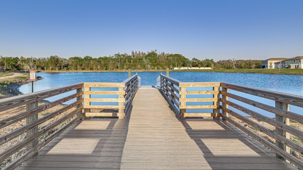 Eine hölzerne Pier, die zu einem Gewässer mit blauem Himmel führt.