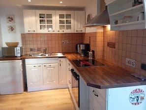 A kitchen with white cabinets, a wooden countertop, a sink, a coffee maker, and a toaster.