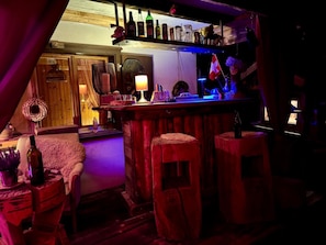 A bar area with stools, a shelf with bottles, and a lamp.