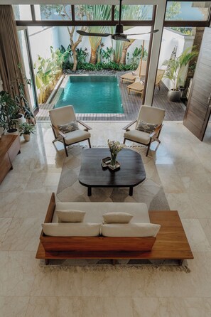 Un espace de vie moderne avec une piscine, des chaises longues et un canapé.