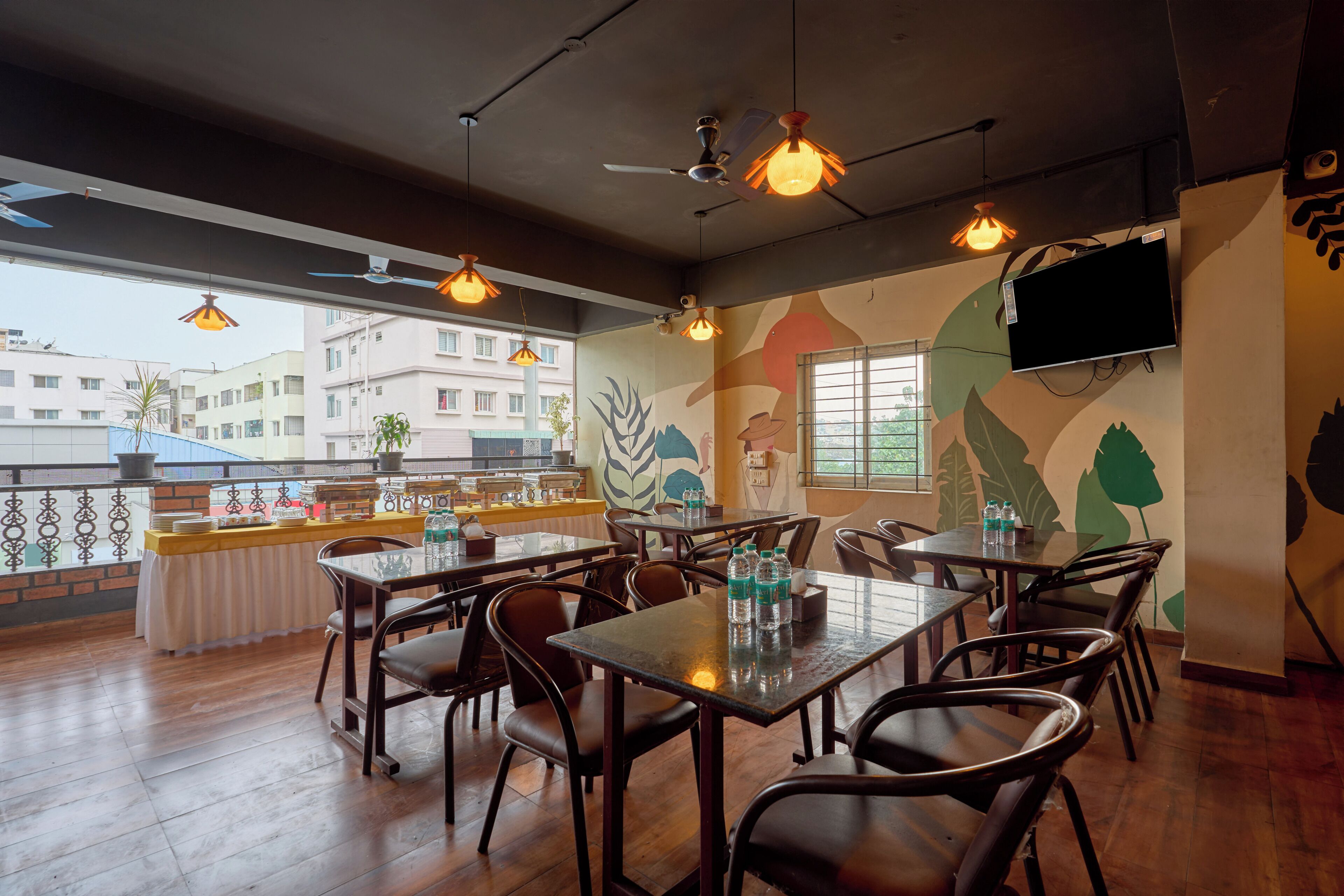 A restaurant with multiple tables and chairs, ceiling fans, and a TV mounted on the wall.
