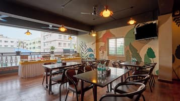 A restaurant with multiple tables and chairs, ceiling fans, and a TV mounted on the wall.