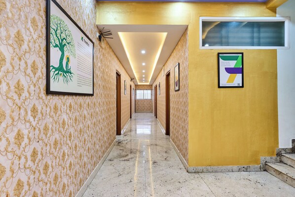 A hallway with patterned wallpaper, framed artwork, and a tiled floor. - Treebo Three Street Inn RR Nagar (Bangalore)