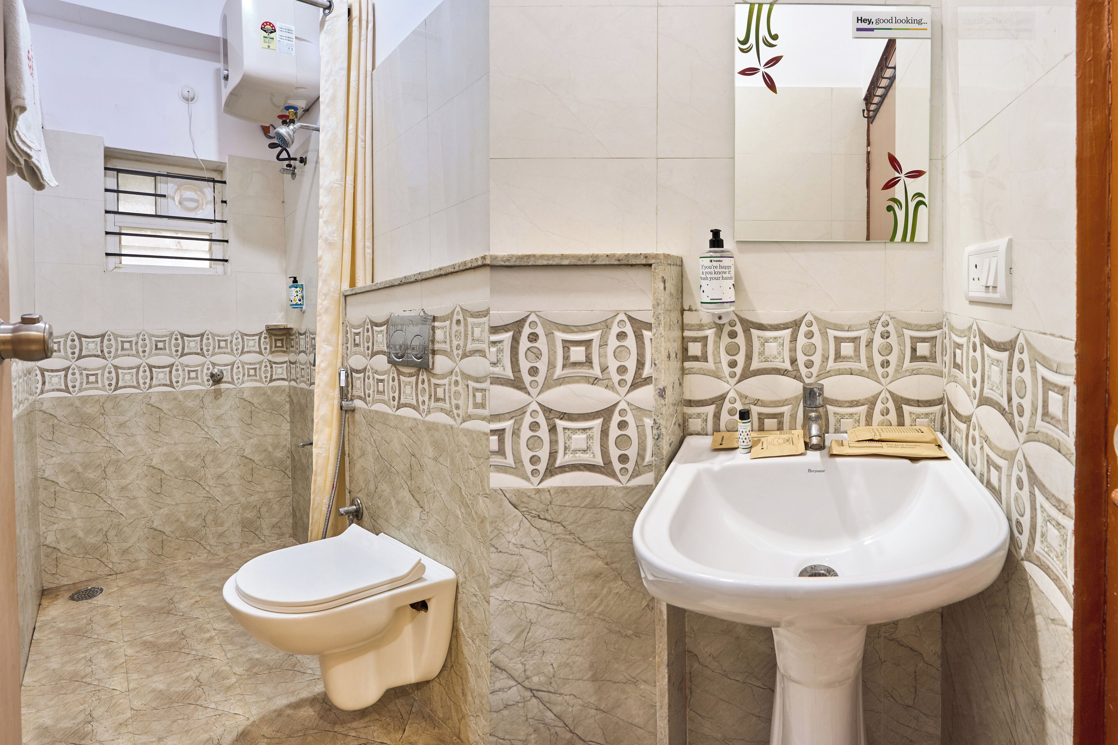 A bathroom with a toilet, bidet, sink, and a mirror with a decorative tile border.