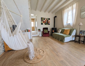 Una sala de estar acogedora con una hamaca, un sofá, una chimenea y un tapete redondo tejido.
